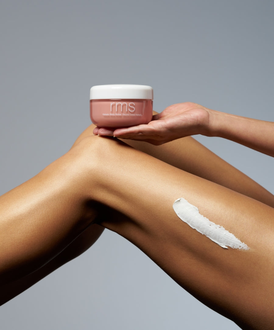 A person holding a jar of Kakadu Body Butter with a smooth creamy application on their leg, showcasing natural, clean beauty body care.