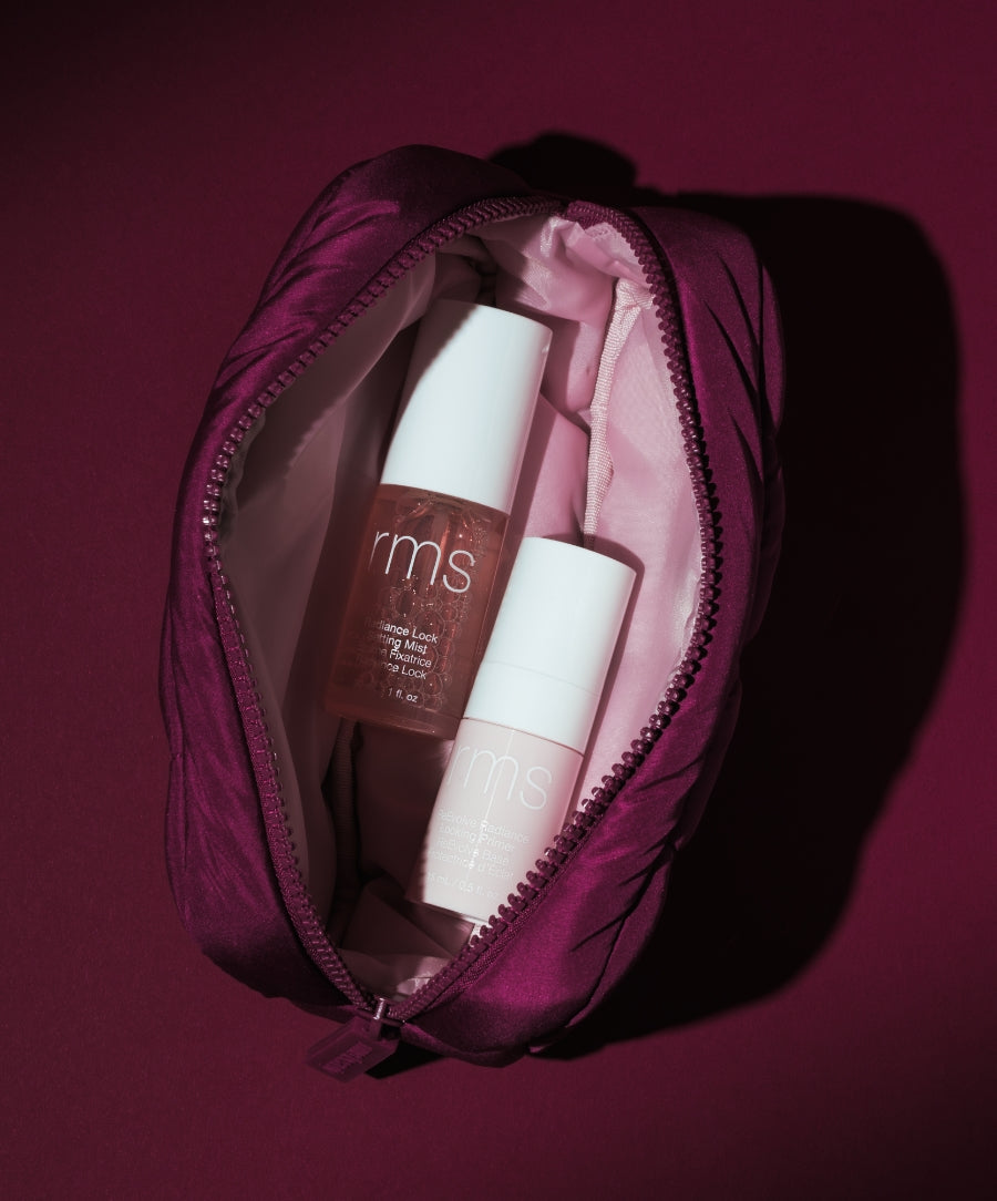 The Travel Prime & Set Duo Pouch open to reveal RMS Beauty makeup products in a burgundy zippered case against a dark background
