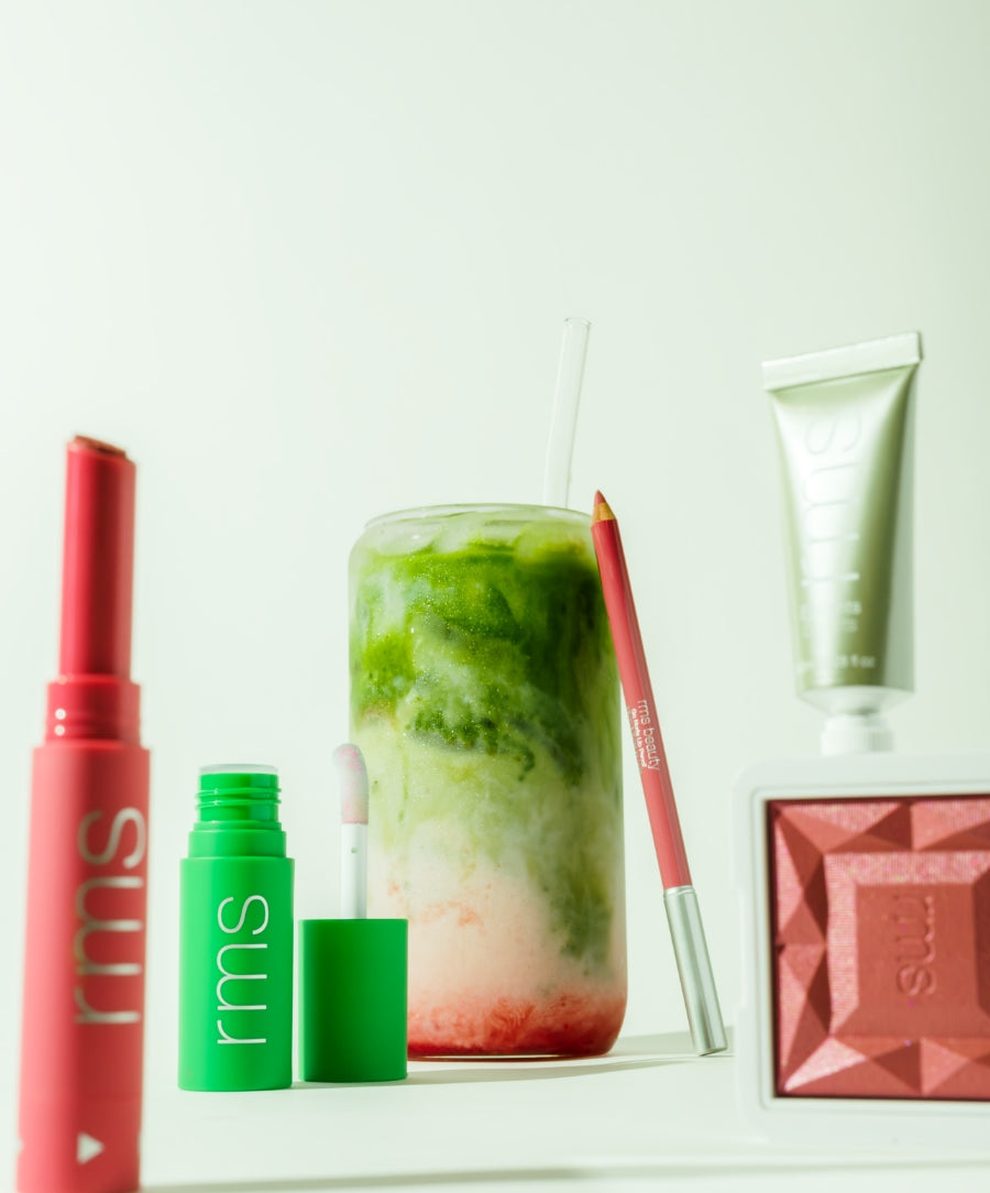 A glass of vibrant strawberry matcha drink surrounded by clean beauty products in green and pink tones, featuring the Color Capsule: Strawberry Matcha and sustainable packaging.
