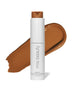 ReEvolve Natural Finish Liquid Foundation in a sleek white bottle with a warm medium brown shade swipe behind, showcasing clean beauty and natural ingredients in sustainable packaging.