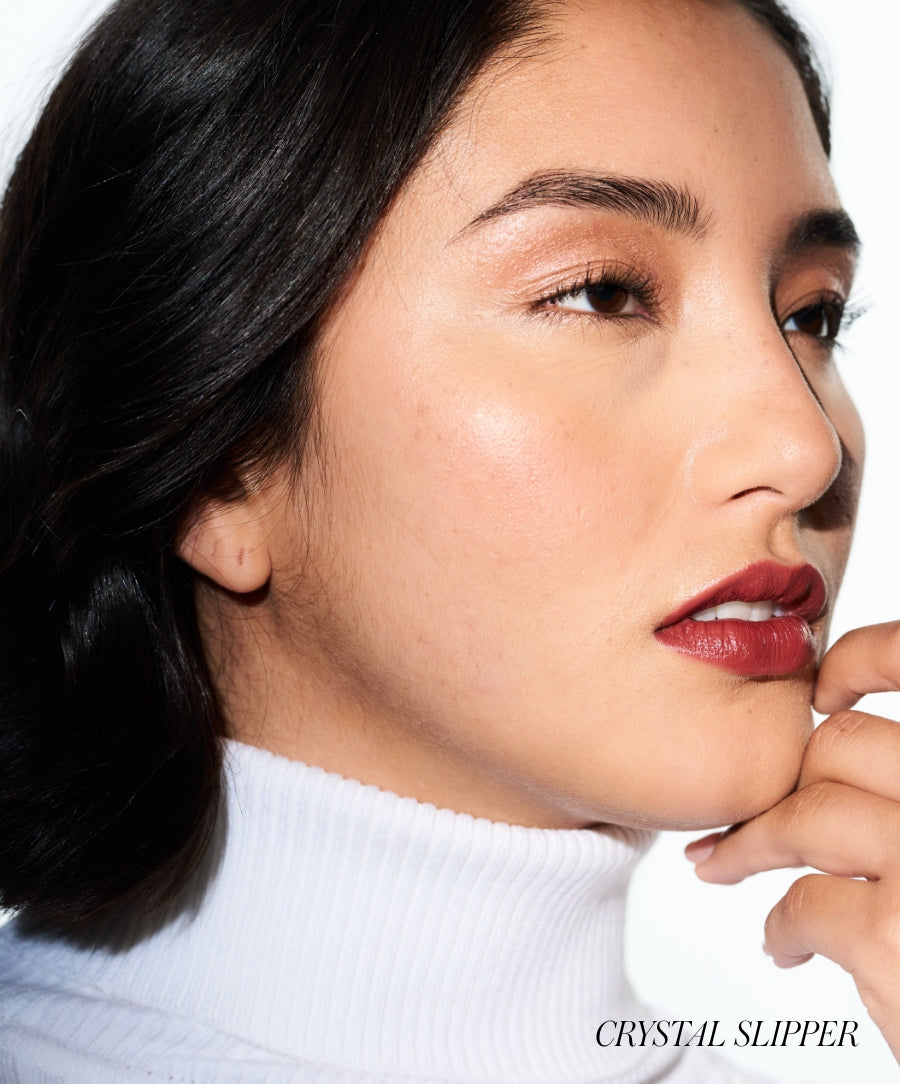 Close-up of a woman wearing deep red lipstick and subtle natural makeup, highlighting radiant skin with a clean beauty look using Lip2Cheek.
