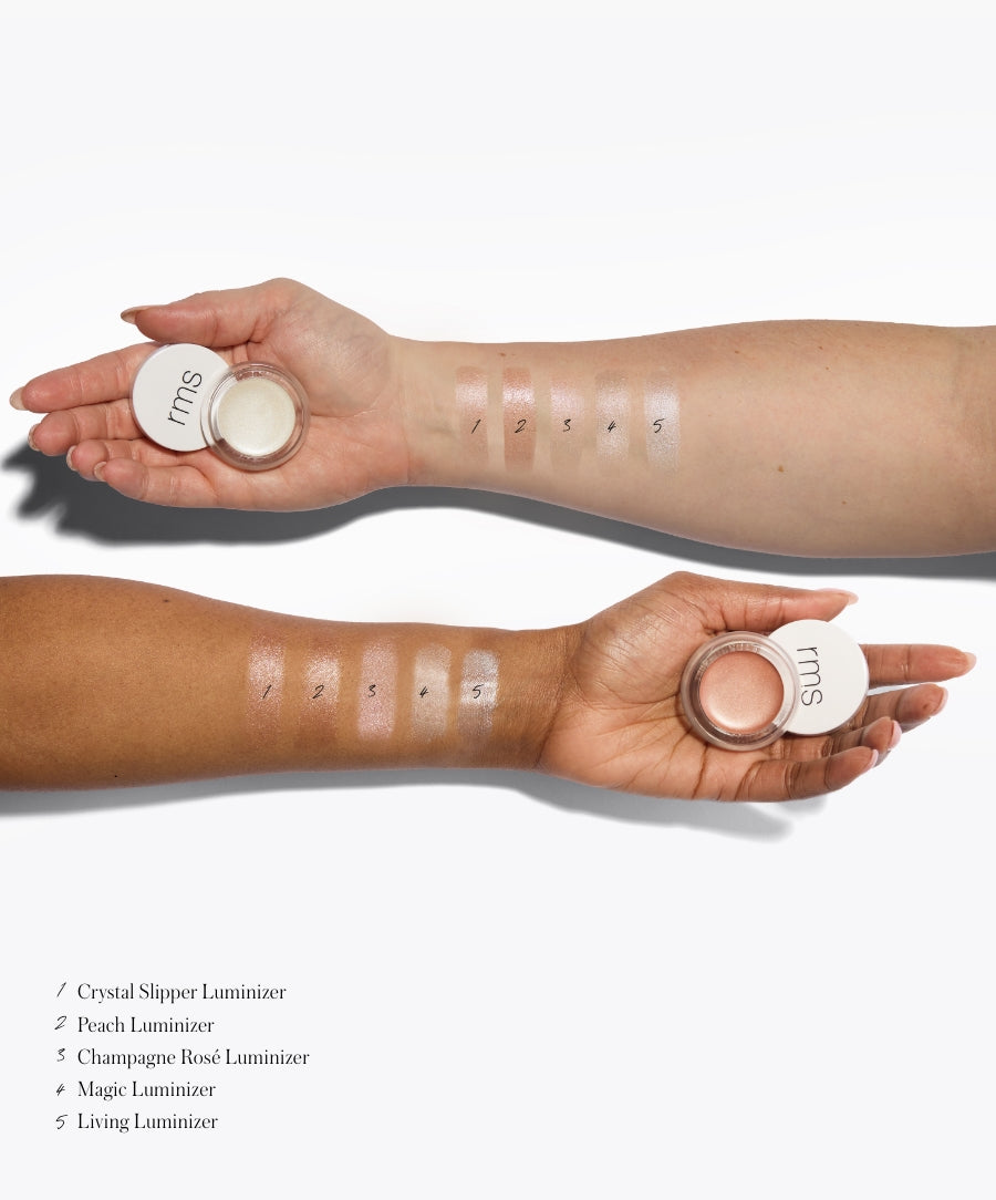 Two arms with different skin tones showing swatches of five shades of Luminizer makeup, each hand holding a small RMS Beauty container with the product inside, demonstrating natural ingredients and clean beauty.