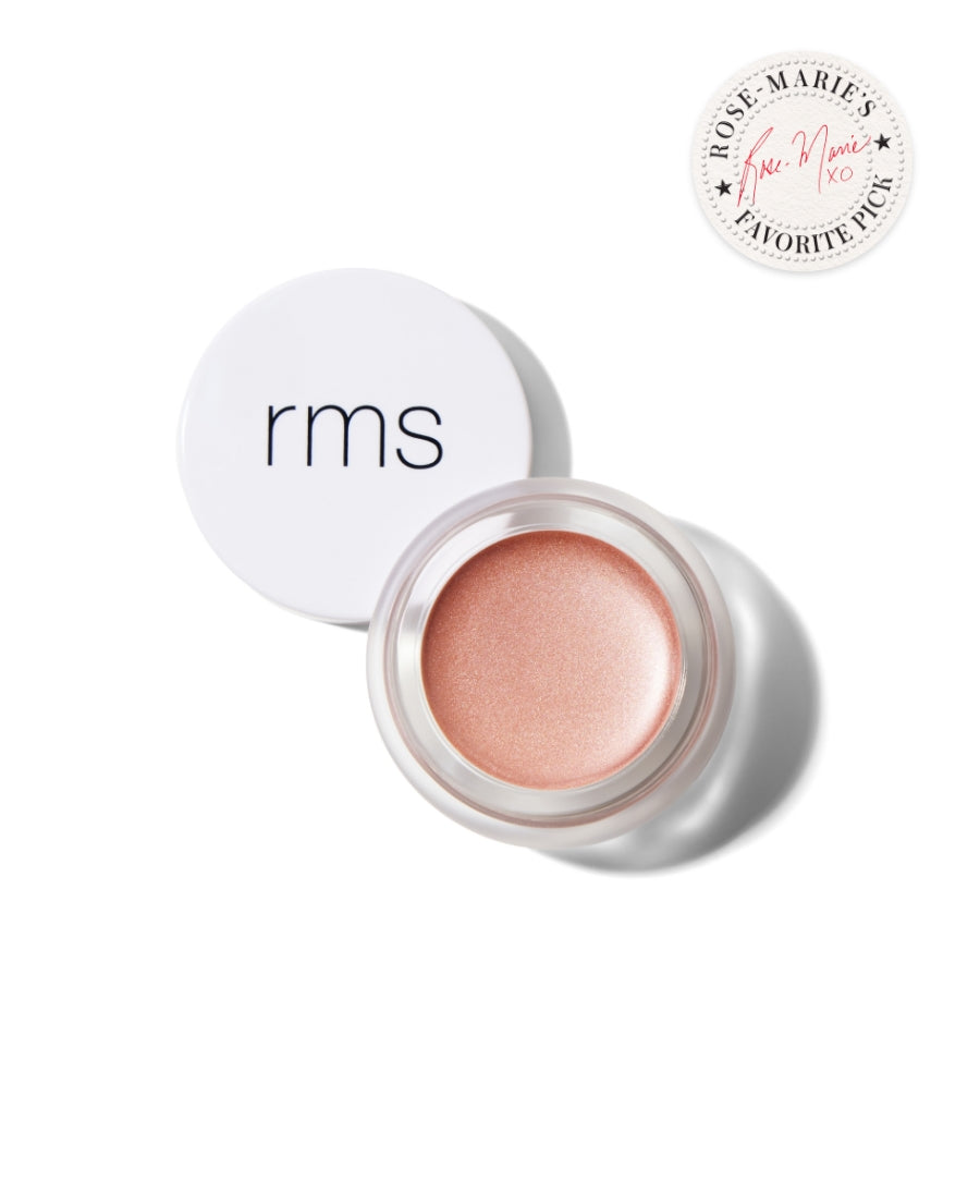 Open jar of RMS Beauty Luminizer with creamy light peach highlighter beside white lid, showcasing clean beauty and natural ingredients for radiant makeup glow.