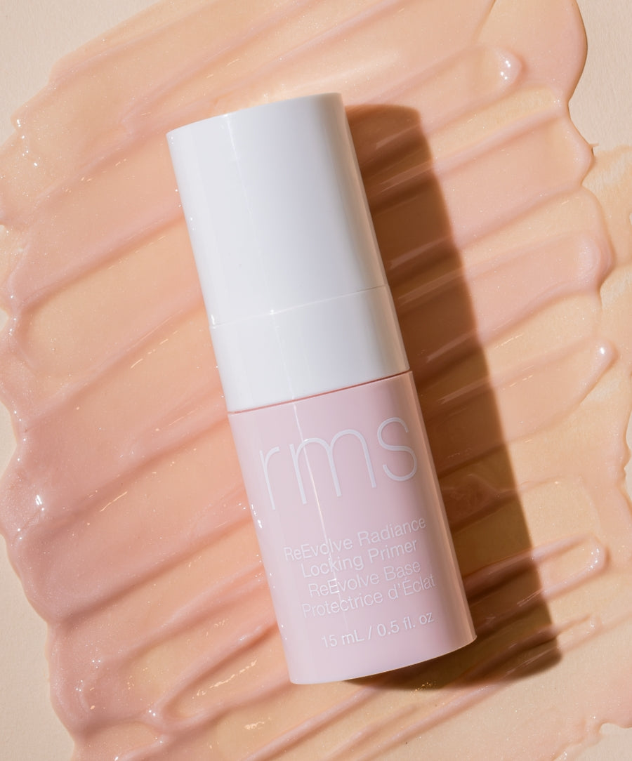 ReEvolve Radiance Locking Primer bottle placed on a smooth, glossy peach-toned texture, highlighting its clean beauty and skincare infused makeup qualities.