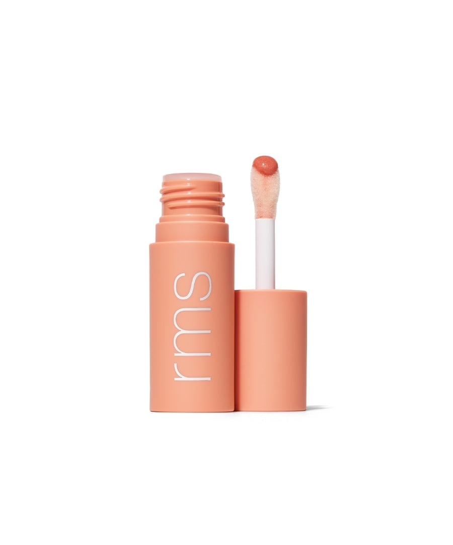 Open tube of Legendary Lip Oil with soft peach-colored packaging and a doe-foot applicator showing a glossy, tinted lip oil on the tip.
