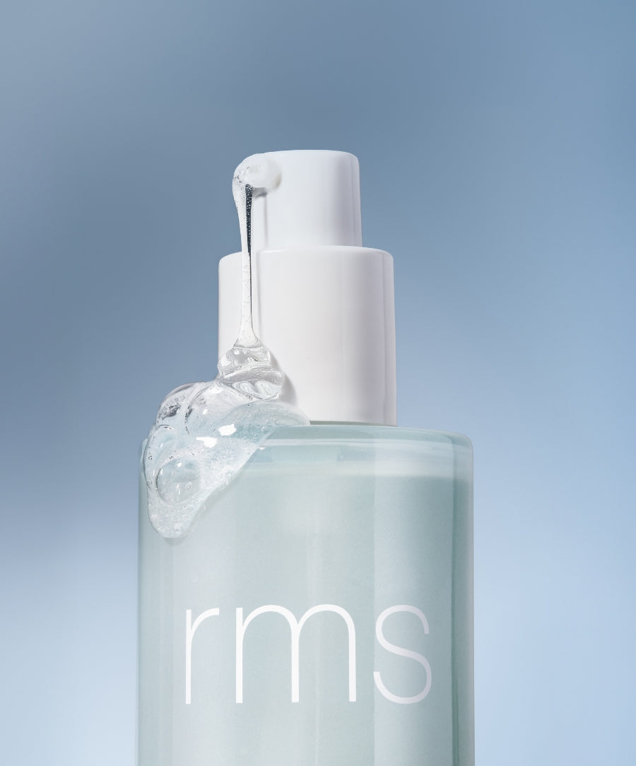 Clear gel texture dripping from the white pump of a translucent light blue bottle labeled rms, representing the Kakadu Clean Cleansing Gel with clean ingredients and sustainable packaging.