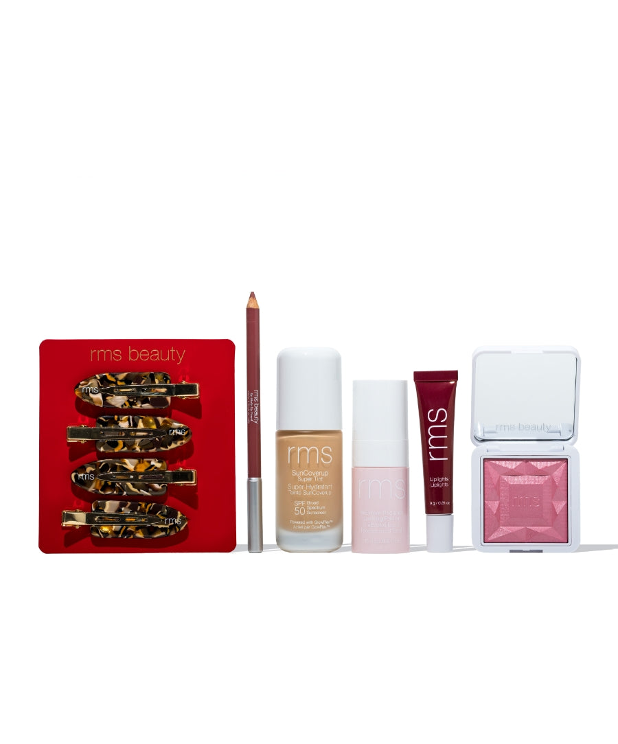 RMS Discovery Kit featuring a set of cruelty free makeup products including hair clips, lip pencil, foundation, skincare spray, lip gloss, and pink blush compact.