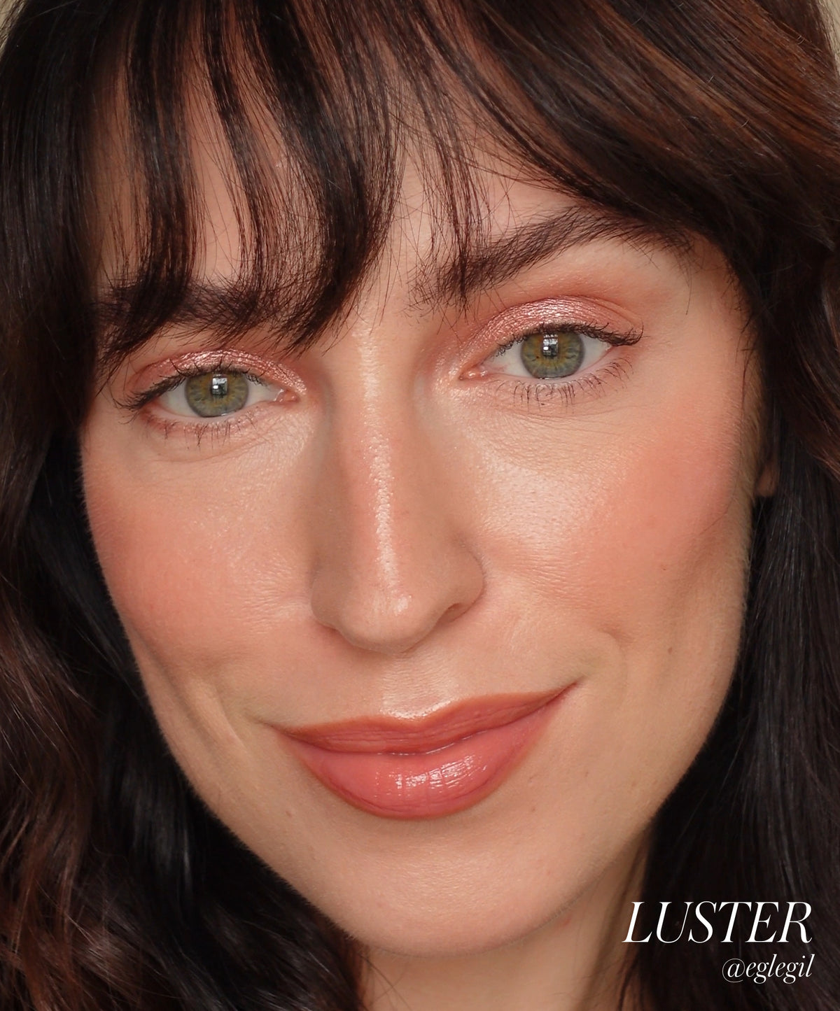 Close-up of a woman wearing shimmering peach eyeshadow applied with Eyelights Cream Eyeshadow, showcasing natural skin with a soft, radiant finish and subtle glossy lips, highlighting clean beauty and natural ingredients.