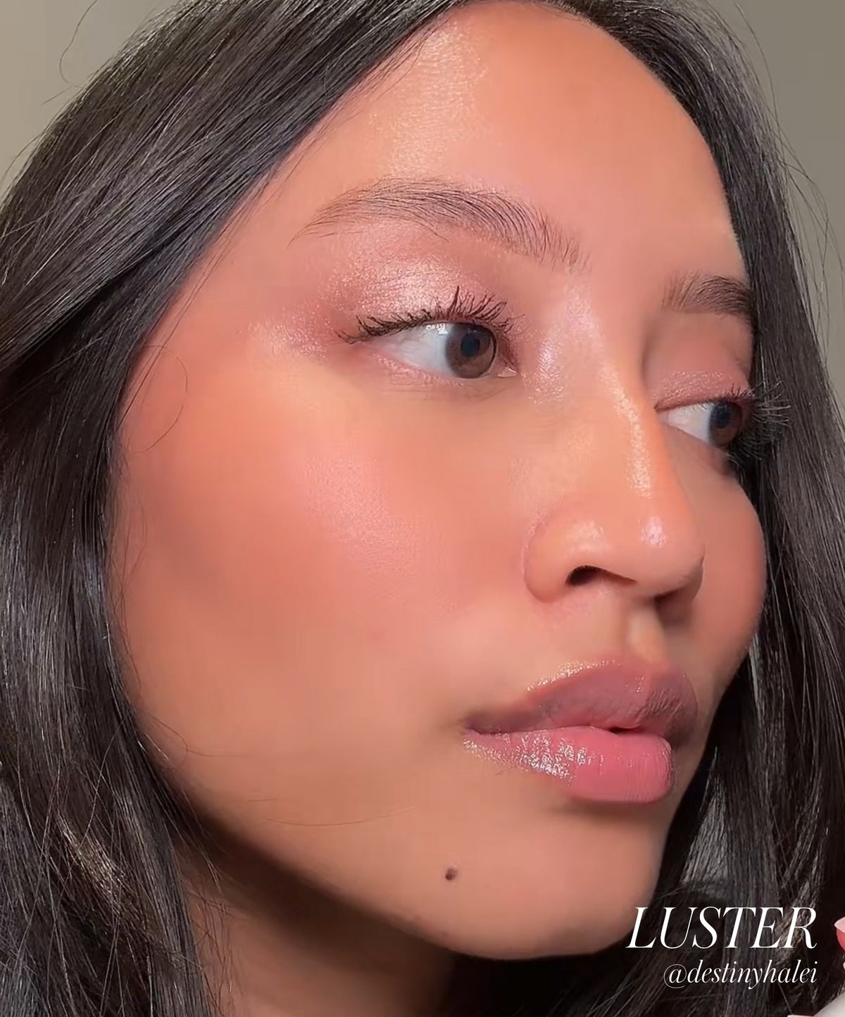 Close-up of a woman wearing natural, radiant makeup highlighting soft shimmer on her eyelids, showcasing the Eyelights Cream Eyeshadow in a clean beauty style.