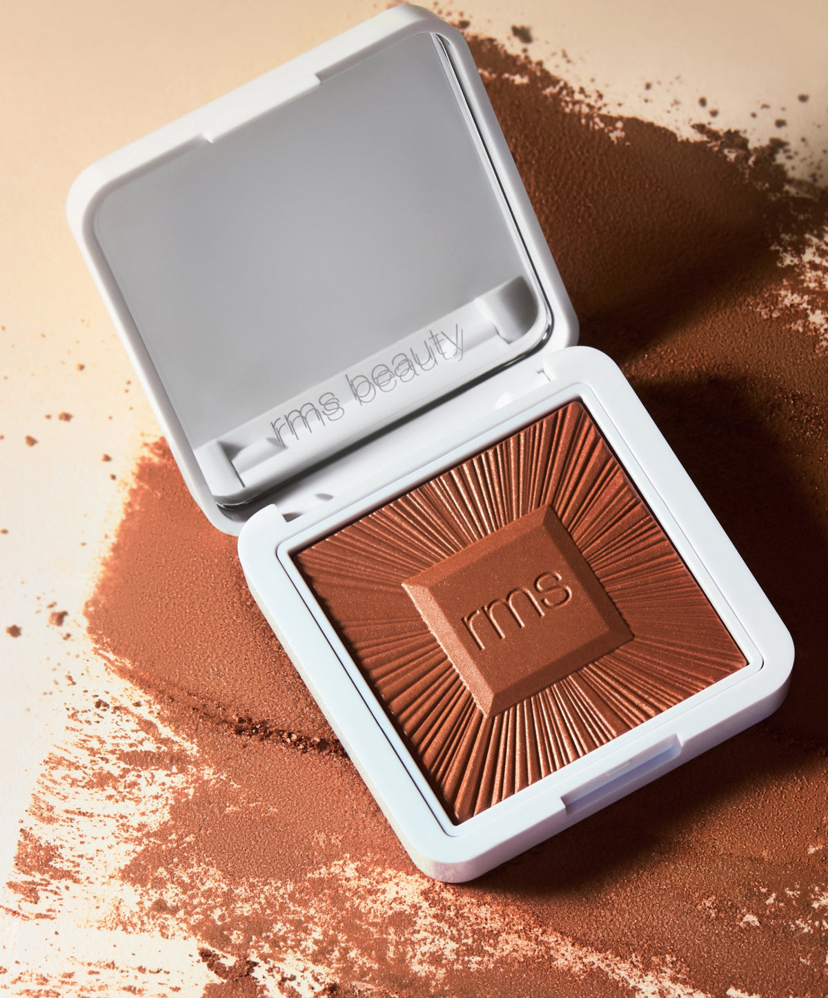 Open compact of ReDimension Hydra Bronzer with rich, warm brown powder and a sunburst textured design, styled on scattered bronzer powder.