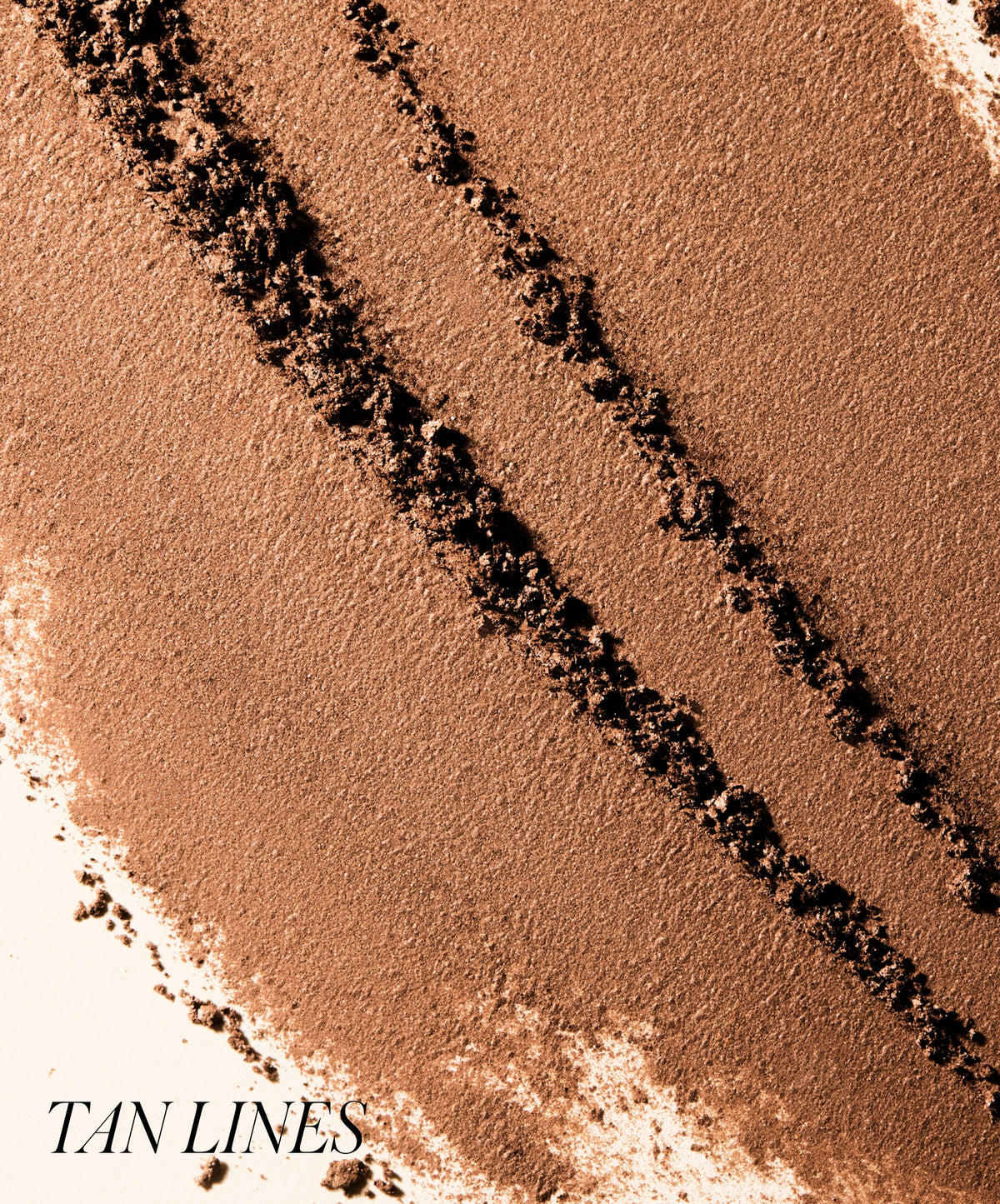 Close-up of tan shades of crushed powder makeup in smooth and textured swatches labeled Tan Lines, showcasing ReDimension Hydra Bronzer for natural sun-kissed color and clean beauty benefits.