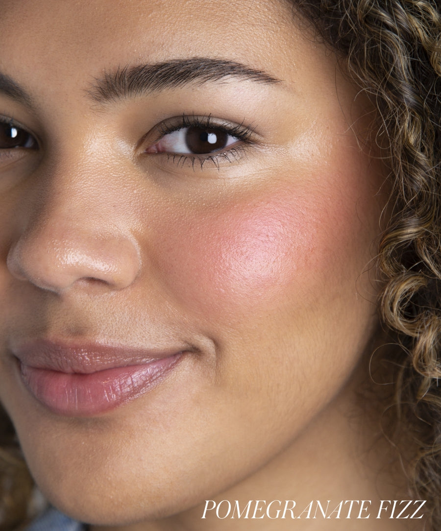 Close-up of a woman with natural skin wearing ReDimension Hydra Powder Blush in Pomegranate Fizz, showcasing a clean beauty look with glowing, radiant cheeks.