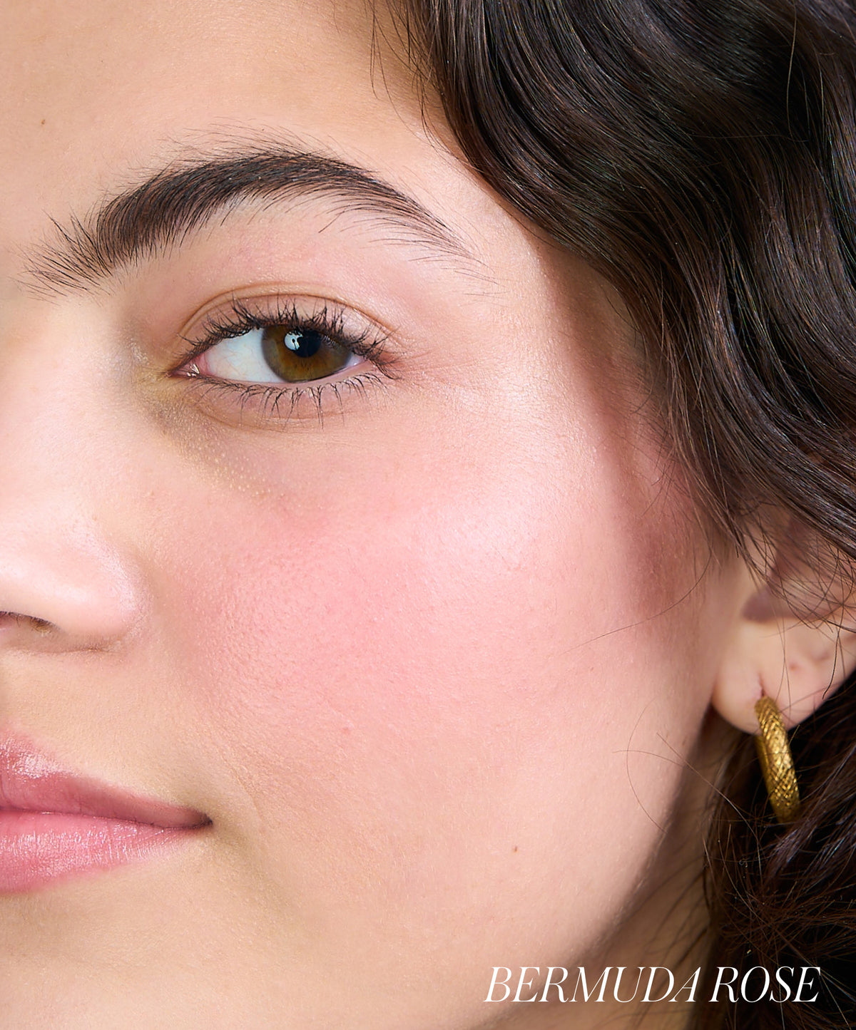 Close-up of a woman's face showing natural, glowing skin with soft pink cheeks enhanced by ReDimension Hydra Powder Blush in a Bermuda Rose shade, highlighting clean beauty and skincare infused makeup.