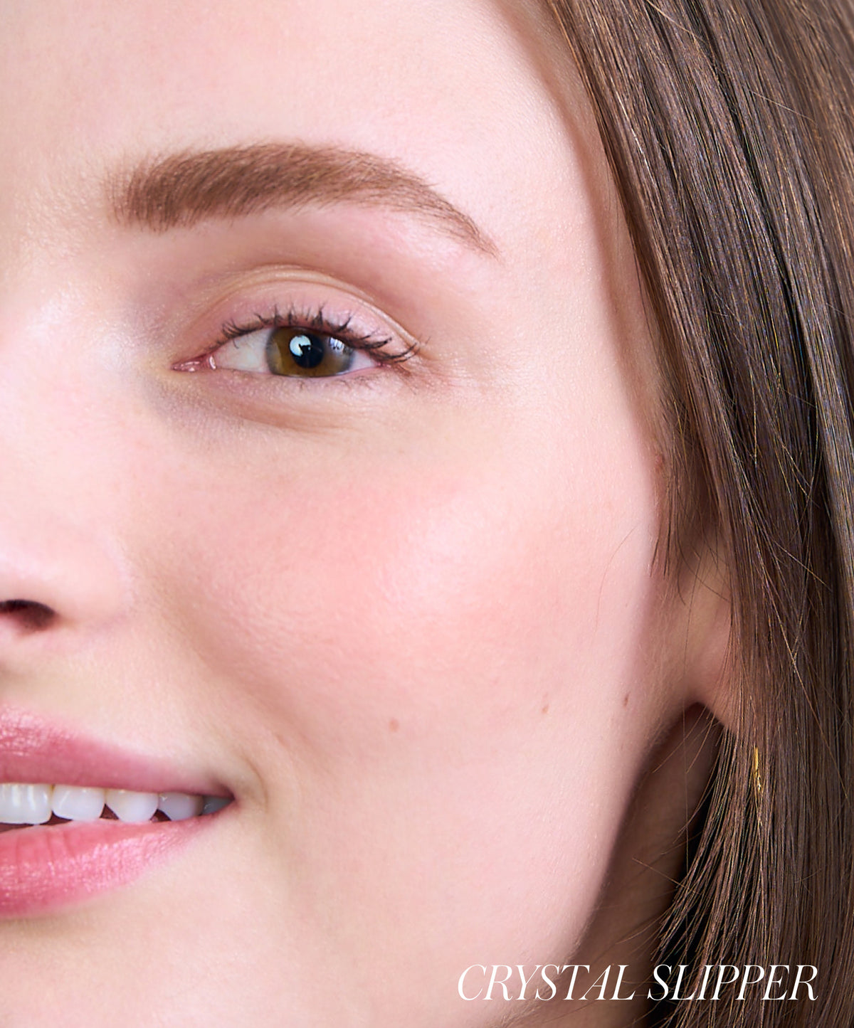 Close-up of a smiling woman with natural makeup showcasing smooth, radiant skin and subtle blush on her cheek, highlighting the effect of ReDimension Hydra Powder Blush.