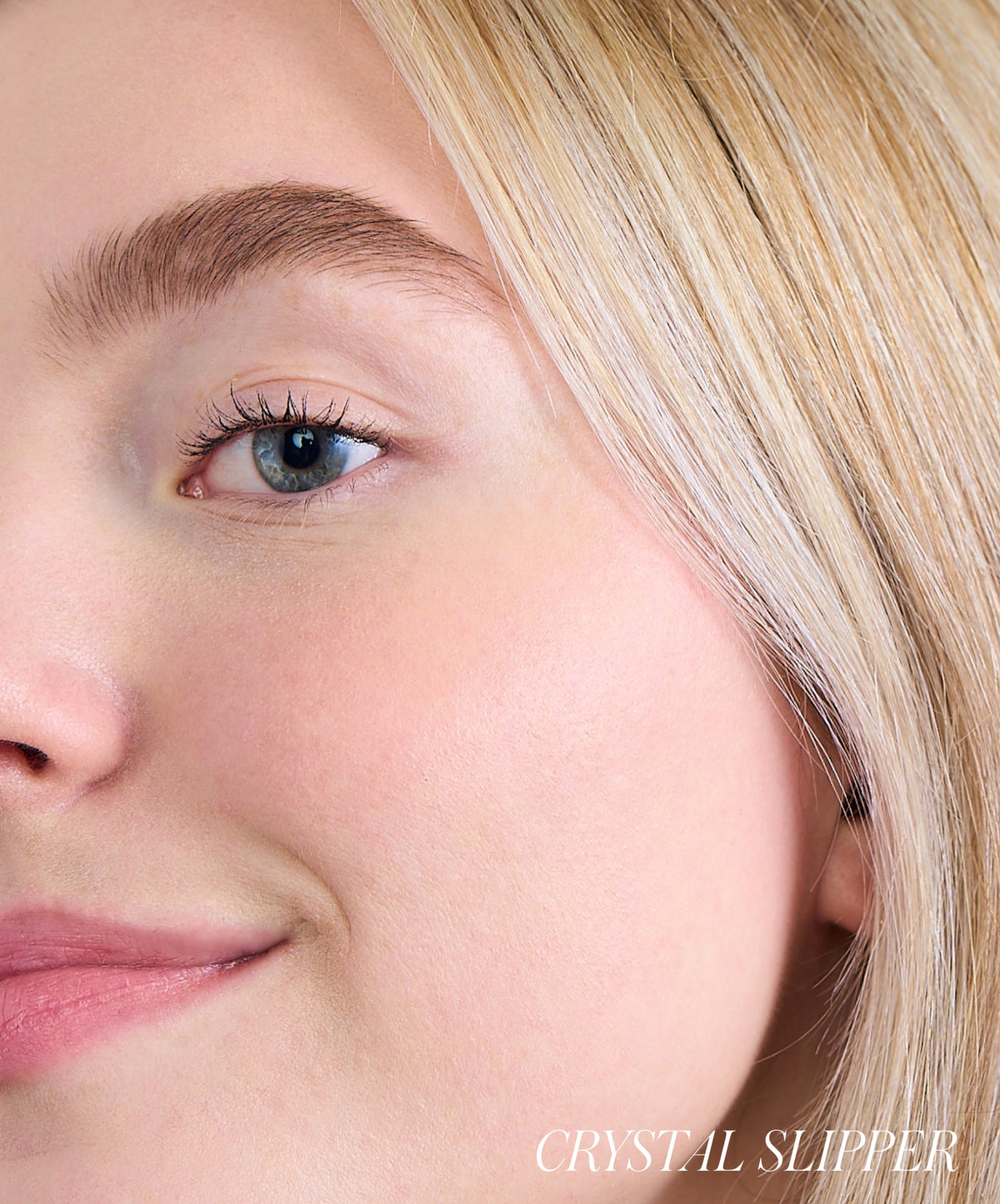 Close-up of a woman's face showcasing natural, dewy skin with subtle rosy cheeks, highlighting the effect of ReDimension Hydra Powder Blush in a light pink shade.