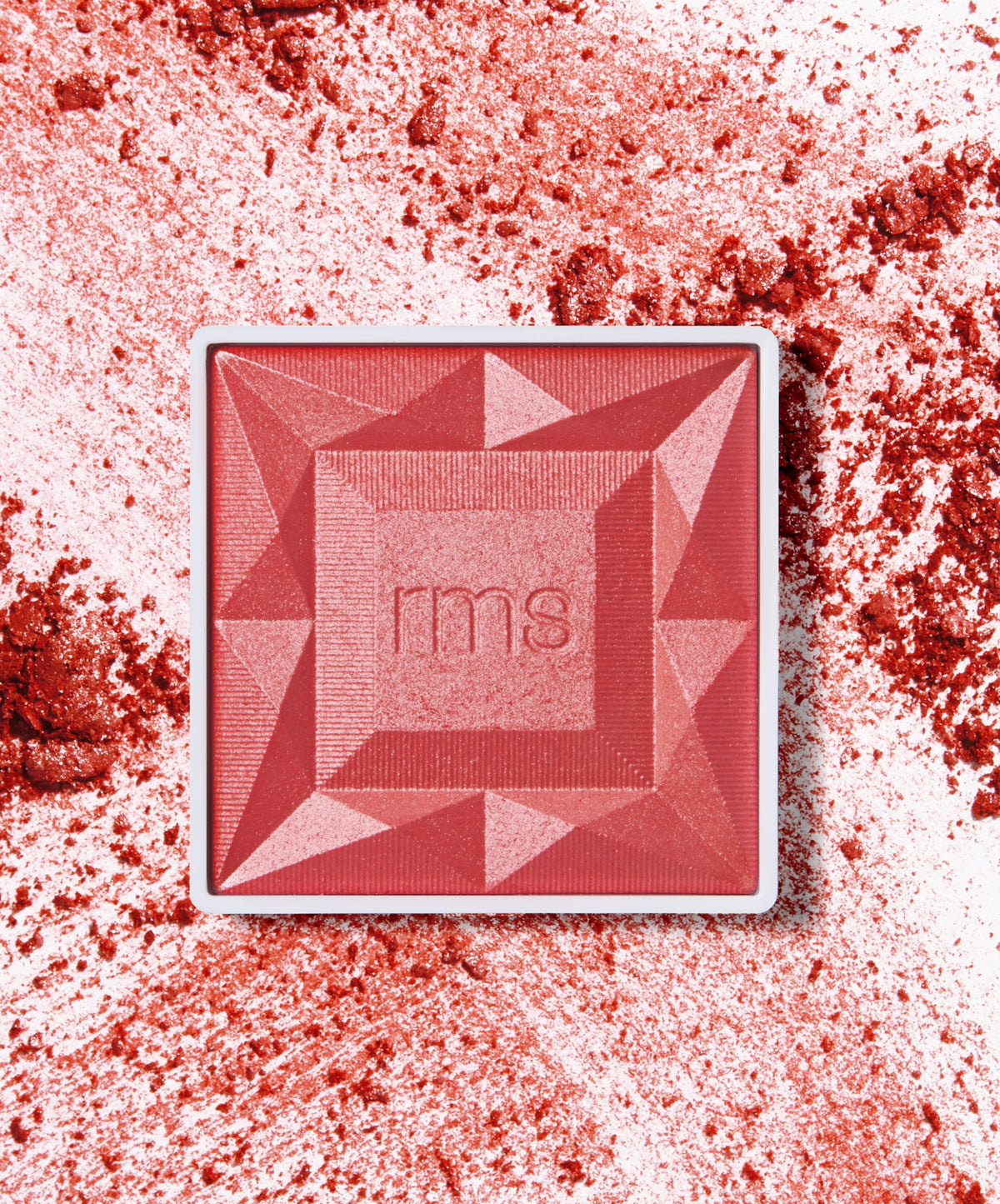 ReDimension Hydra Powder Blush in a geometric compact with vibrant red and pink tones, surrounded by crushed powder highlighting its smooth texture and rich pigmentation.