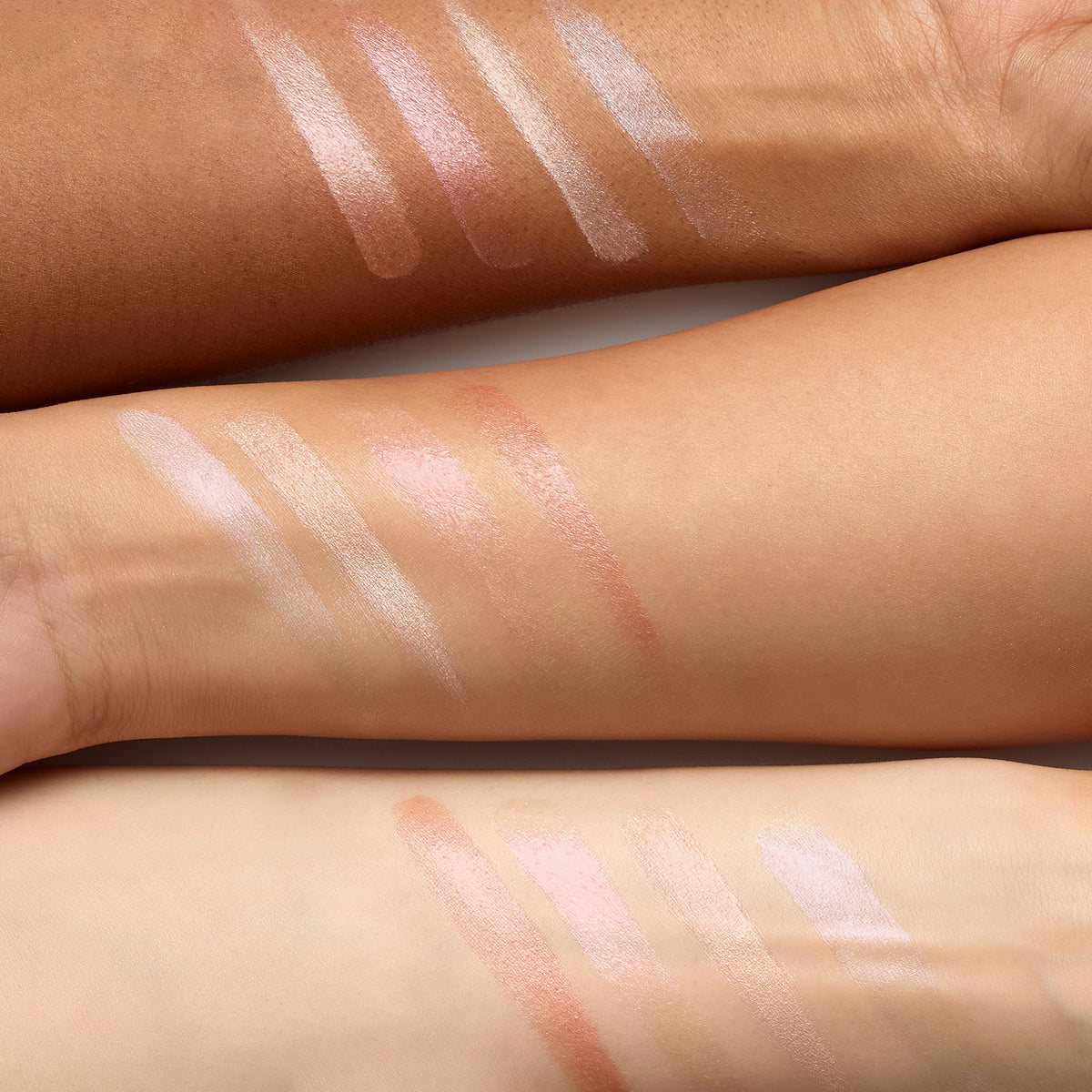 Swatches of Luminizer highlighter shades displayed on three different skin tones, showcasing natural, radiant, and glowing finishes suitable for diverse complexions.