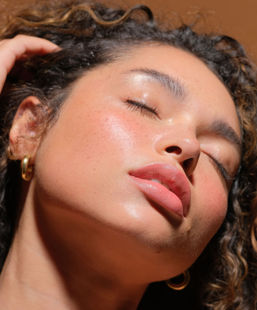 Close-up of a woman with glowing, radiant skin highlighting a natural makeup look enhanced by Luminizer, showcasing a dewy finish and healthy complexion.