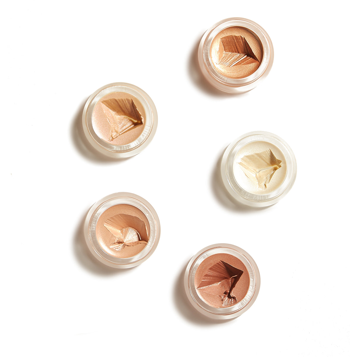 Five small open jars of Luminizer makeup in varying shades from light to medium on a white background, showcasing a creamy texture and natural tones.