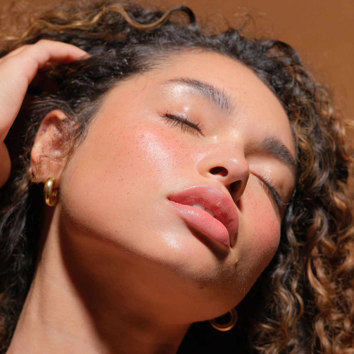 Close-up of a woman with glowing skin and natural makeup showcasing the radiant effect of Luminizer, highlighting clean beauty and skincare infused makeup benefits.