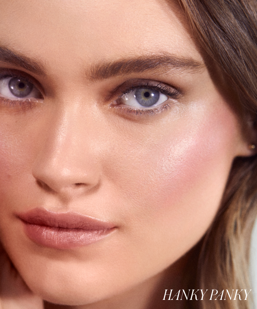 Close-up of a woman’s face showcasing a natural, radiant makeup look with soft pink tones on her cheeks and lips, highlighting the glow from ReDimension Hydra Powder Blush.
