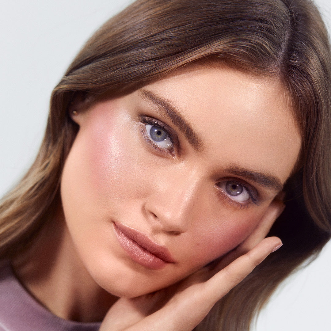 Close-up of a woman with radiant skin wearing natural makeup, highlighting the soft pink glow from ReDimension Hydra Powder Blush on her cheeks, emphasizing clean beauty and skincare infused makeup.