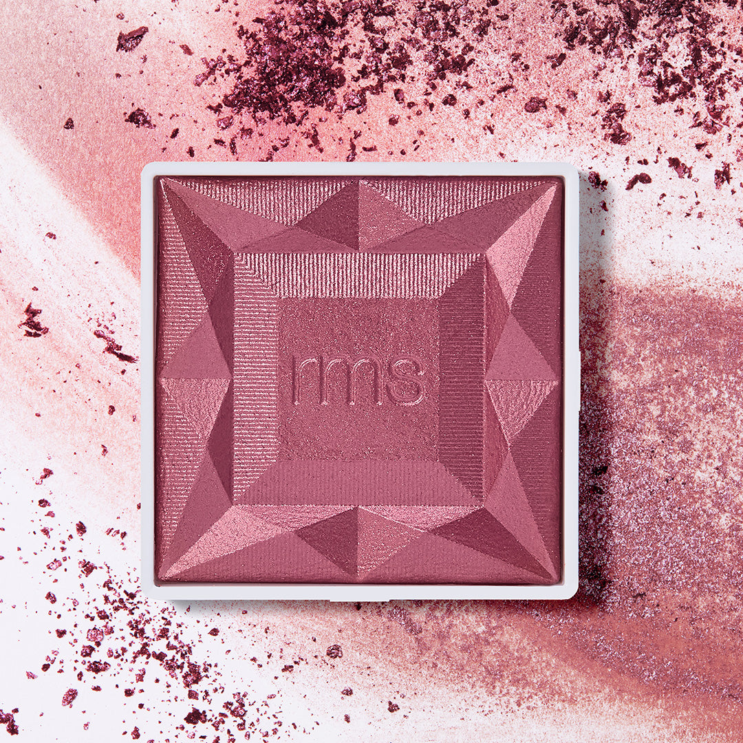 ReDimension Hydra Powder Blush in a rich mauve shade with a geometric embossed design, surrounded by crushed powder highlighting its smooth, natural ingredients and clean beauty appeal.