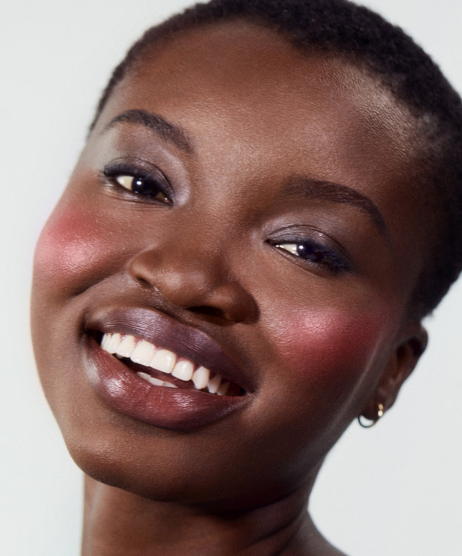 Close-up of a smiling woman with radiant skin wearing ReDimension Hydra Powder Blush in a natural, dewy makeup look promoting clean beauty and skincare infused makeup.