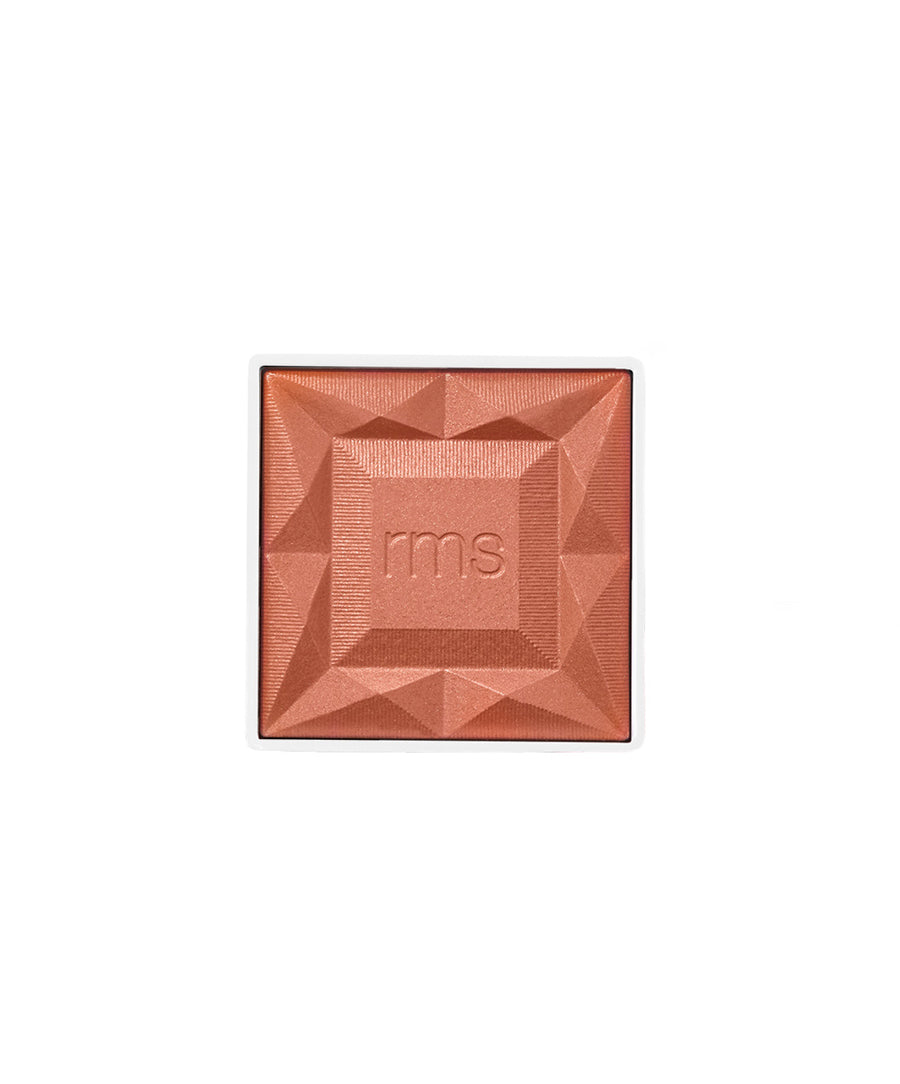 Close-up of a warm coral blush with geometric facets and "rms" embossed in the center, showcasing the ReDimension Hydra Powder Blush designed with natural ingredients and clean beauty principles.