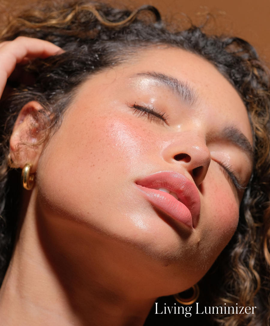 Close-up of a woman with glowing skin and natural makeup wearing gold hoop earrings, highlighting a radiant complexion enhanced by Luminizer.