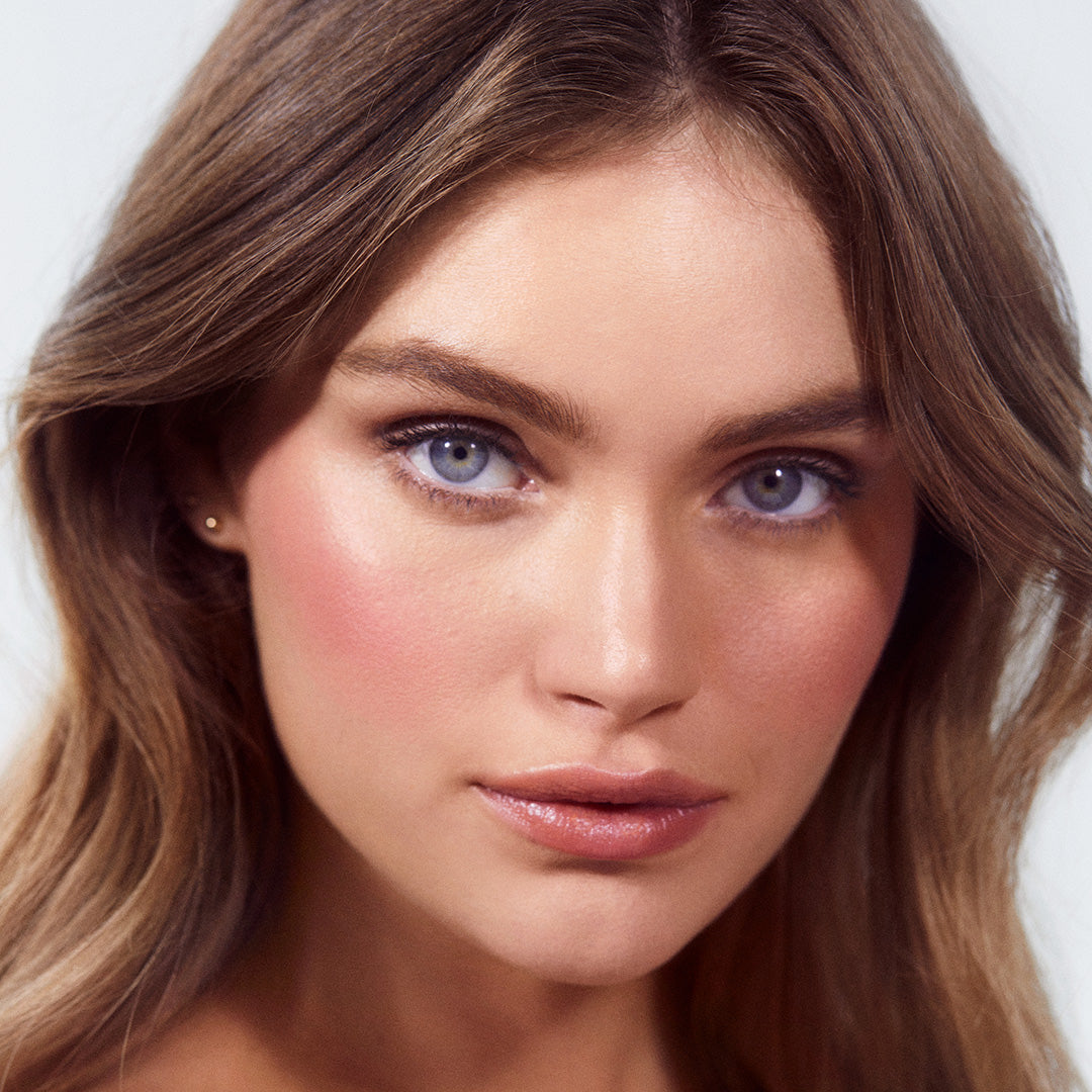 Close-up of a woman with glowing skin and natural makeup, highlighting soft pink cheeks enhanced with ReDimension Hydra Powder Blush for a radiant, fresh look.