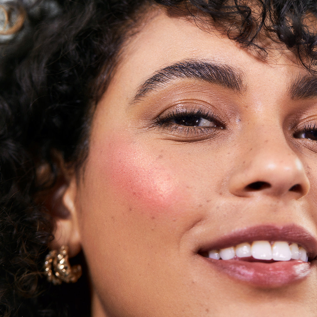 Close-up of a smiling woman with natural makeup showcasing a radiant pink cheek glow achieved using ReDimension Hydra Powder Blush, highlighting clean beauty and natural ingredients.