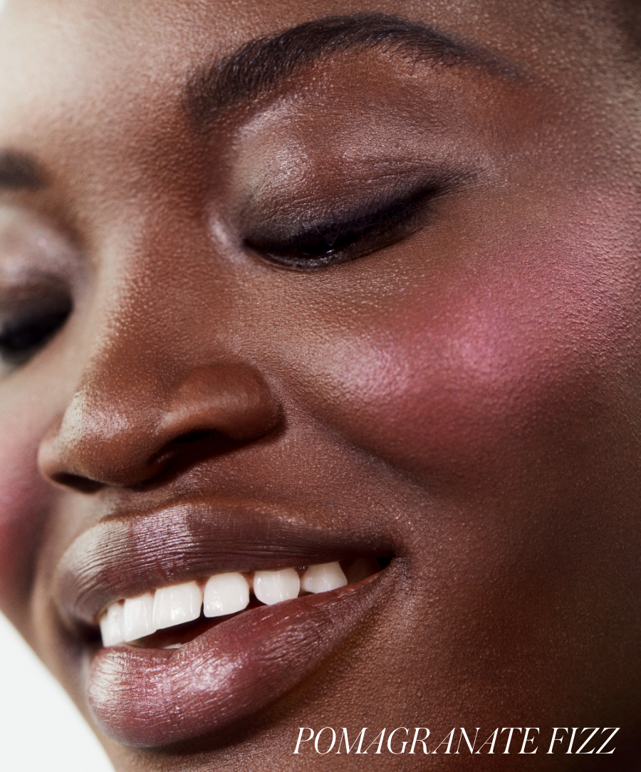 Close-up of a smiling person with smooth skin wearing ReDimension Hydra Powder Blush in a vibrant pomegranate fizz shade, highlighting natural ingredients and clean beauty benefits.