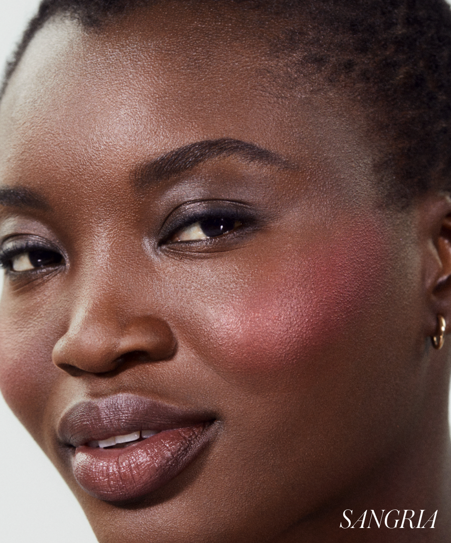 Close-up of a woman with glowing skin wearing ReDimension Hydra Powder Blush in a rich sangria shade, showcasing natural ingredients and clean beauty makeup.