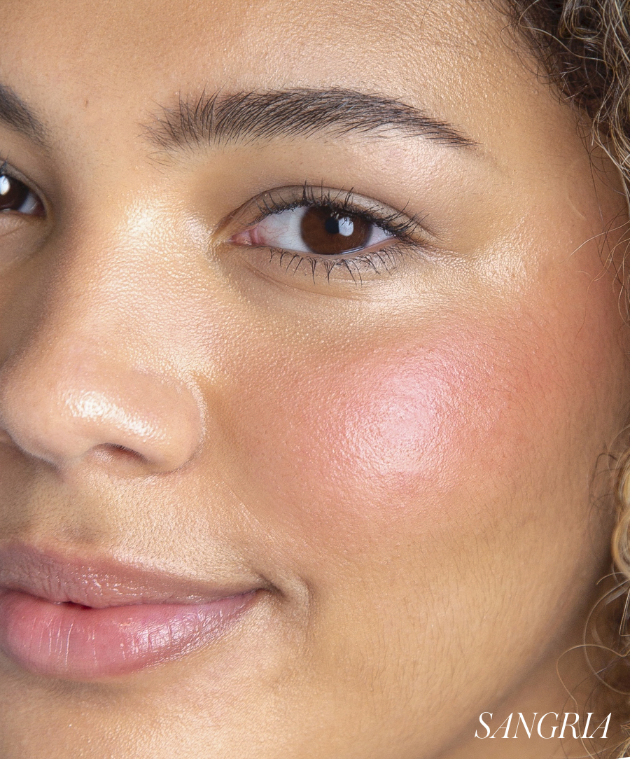 Close-up of a woman with smooth skin wearing ReDimension Hydra Powder Blush in a natural rosy shade on her cheek, showcasing clean beauty and skincare infused makeup.